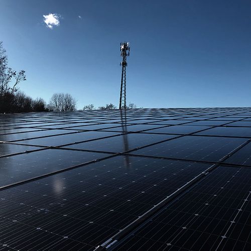 Solar panels mounted on flat roof with communication tower visible